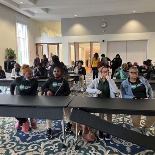 A group of students, sitting near a table.