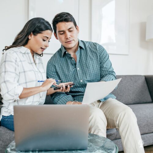 Couple looking over documents while sitting on couch,